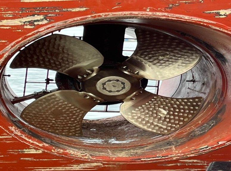 Four-bladed bow thruster propeller inside its tunnel seen through the hull opening