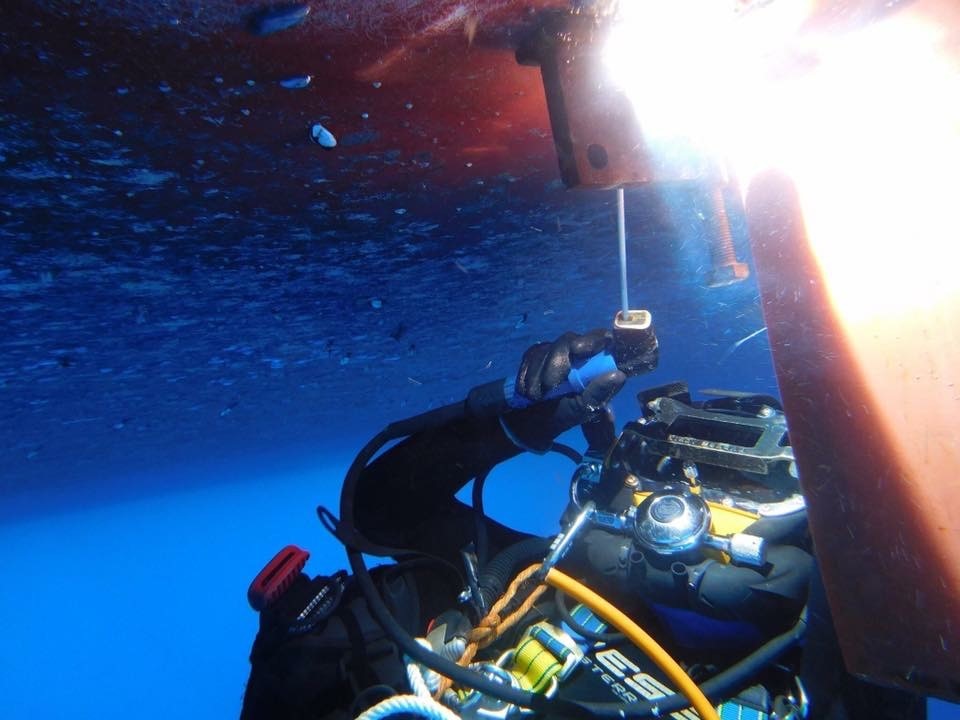 Commercial diver welding underwater beneath a ship's hull