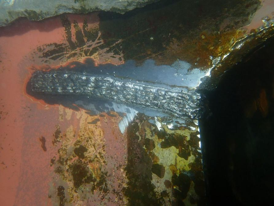 Underwater weld bead along a repaired seam on a ship's hull plating