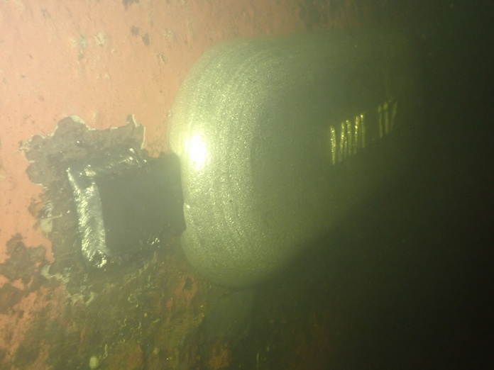 Welded steel pad on a ship's hull beside a large cylindrical underwater fitting