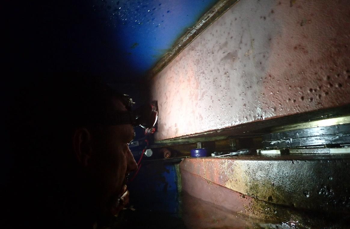 Technician working inside a dry habitat sealed against a vessel's hull